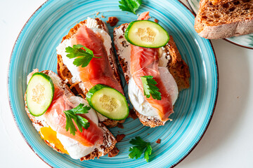 Toast with poached egg, cream cheese and red fish on a blue plate. Delicious and healthy breakfast. Top view