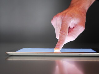 A hand pointing at a tablet screen