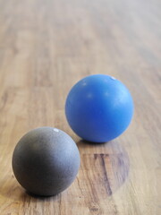 Two balls, one blue and one gray, are sitting on a wooden floor