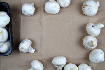 White champignons scattered on craft background. Space for text