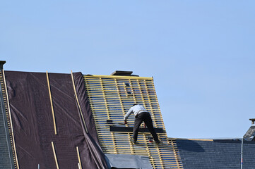 ouvrier couvreur sur un toit d'habiation en cours de rénovation