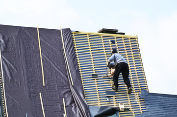 ouvrier couvreur sur un toit d'habiation en cours de rénovation