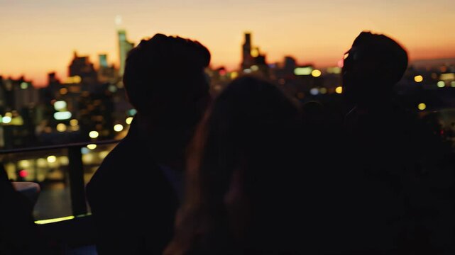 Group of friends at rooftop party with city skyline at sunset