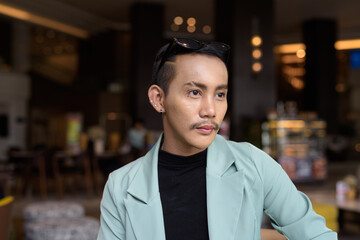 Fototapeta premium Portrait of nonbinary genderfluid young Asian gay man in cafe