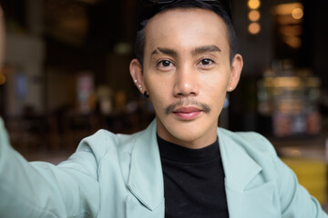 Portrait of nonbinary genderfluid young Asian gay man taking POV selfie