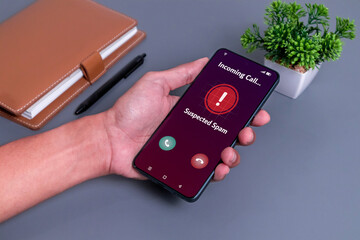 Spammer incoming call concept. Hand holding smartphone with incoming call from unknown caller on phone screen.