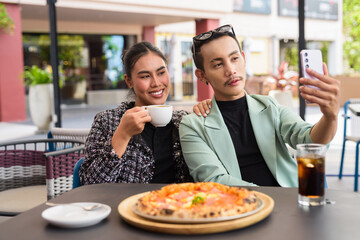 Happy friends outdoors eating pizza together in restaurant