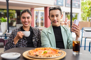 Happy friends outdoors eating pizza together in restaurant