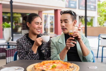 Happy friends outdoors eating pizza together in restaurant