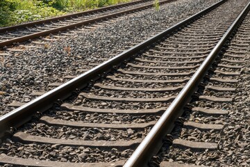 Close-up of railway tracks extending into the distance on sunny day