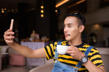 Portrait of nonbinary genderfluid young Asian gay man in coffee shop