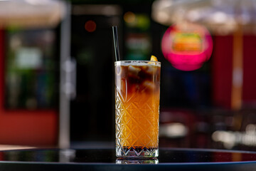 Espresso tonic cocktail in a glass glass with a straw on a table on a summer terrace in a cafe