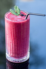 Berry smoothie in a tall glass with straw