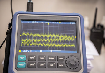 Digital close-up image of an oscilloscope screen displaying real-time electrical waveforms.