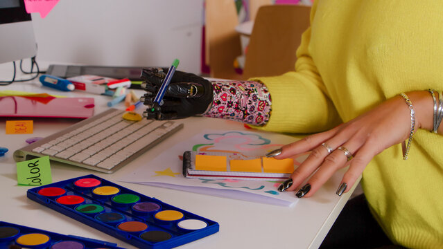 Artistic woman with prosthetic hand painting colorful artwork in creative home studio