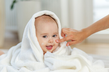 Happy baby getting face cream after bath