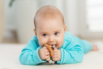 Baby chewing teething ring while lying down. Tummy time