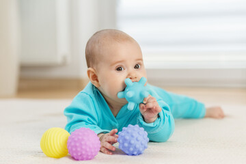 Baby chewing colorful sensory toy balls. Tummy time