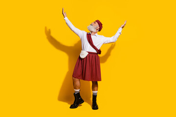 Elderly man elegantly posing in traditional Scottish attire against a vibrant yellow background...