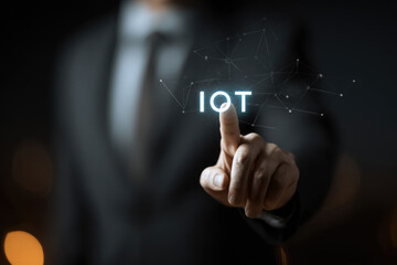 Obraz premium Smart business IOT, internet of things concept. Businessman touching IOT icon on virtual screen, connected internet network to access AI intelligence, business analytics, internet investing