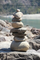 Cairn with river in the background, stacked stones, peaceful setting, serene landscape