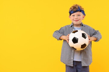 Little boy with soccer ball on yellow background, space for text