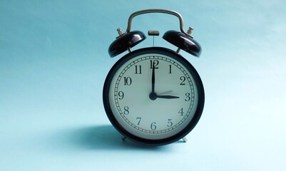 Round black vintage alarm clock isolated on turquoise background.