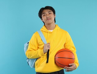 Student with basketball ball and backpack on light blue background