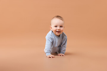 Cute little baby crawling on beige background