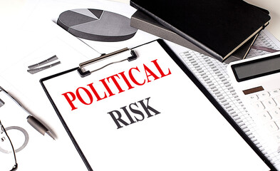 Clipboard with text political risk on desk with charts, calculator, notebook and pen