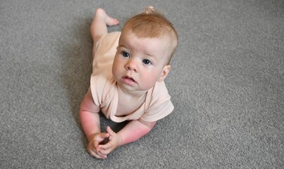 baby crawling on a gray rug. The baby's hands are sunburned