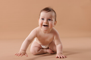 Cute little baby crawling on beige background