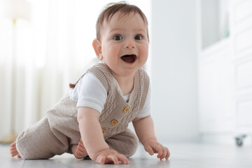 Fototapeta premium Cute little baby crawling on floor at home