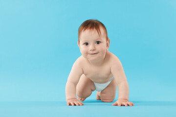 Cute little baby crawling on light blue background