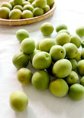 Green plums on a light background. Green plums in a basket.