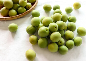 Green plums on a light background. Green plums in a basket.