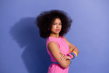 Stylish young woman in a retro pink dress posing confidently against a violet backdrop, showcasing...