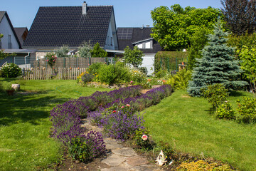 rustical garden - stone paved garden path with flowers and herb spiral