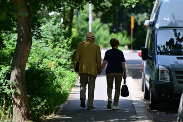 An elder love couple walking together hand in hand on a warm and sunny day in Berlin-City.