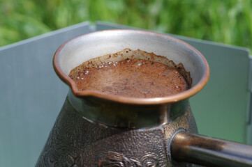 Coffee in a turkish pot on a background of green grass