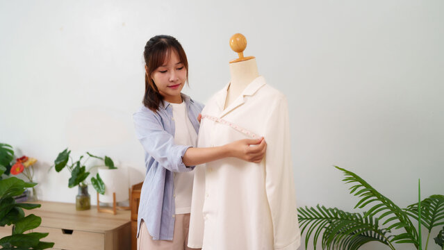 Asian young woman designing clothing measuring mannequin shirt design process in studio fashion designer creative dressmaker tailoring