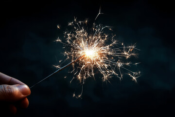 A hand holding a sparkler against a dark background
