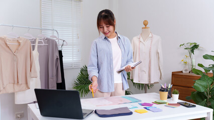 Asian Woman Fashion Designer at Her Studio Designs New Collection Creative Dressmaking Garment...