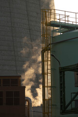 Visible smoke is emanating from the cooling tower of a factory, indicating possible issues with...