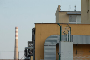 In the background, there is a yellow building that features a prominent chimney, indicating the presence of industrial activity nearby