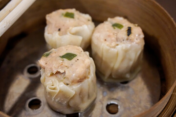 Close up of traditional Dim Sum (siu mai) served in a bamboo steamer