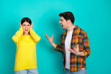 Young couple arguing against a teal turquoise background expressing anger and frustration in casual...