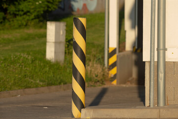 A bright yellow and black striped pole placed prominently in front of a building, standing tall and...