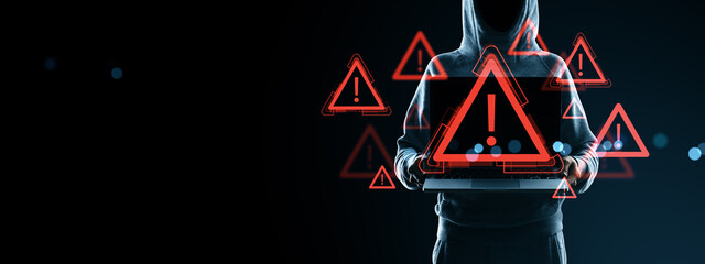 Darknet hacker holding laptop surrounded by digital warning icons in red exclamation signs on black...