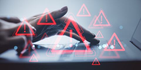 Hands typing on laptop with multiple red exclamation mark warning signs symbolizing cyber danger...